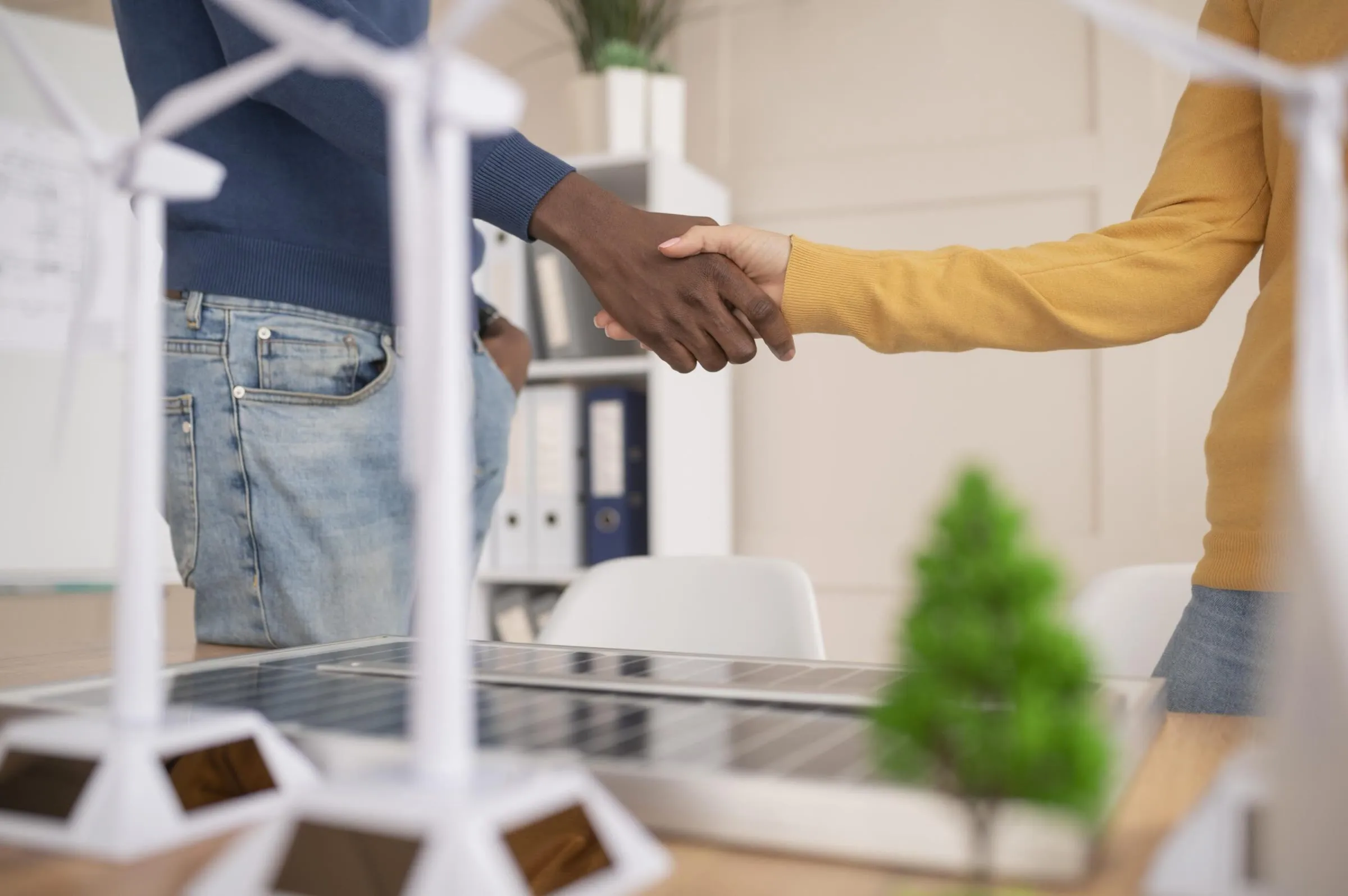 Apretón de manos sobre una maqueta de energía renovable