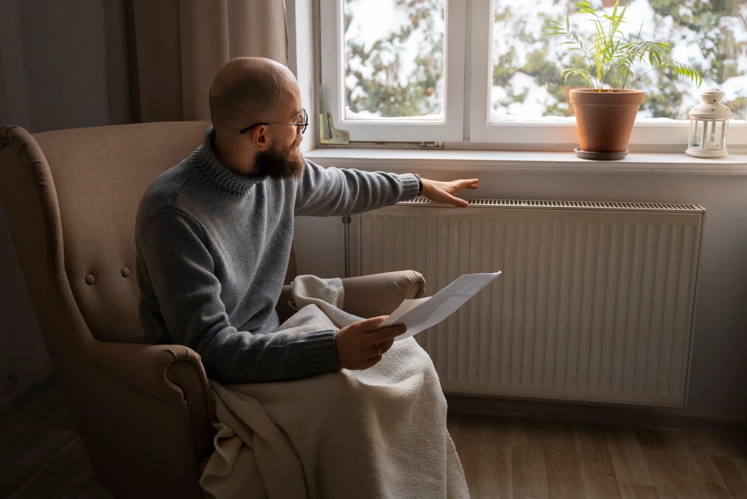 Hombre leyendo su factura sentado junto al radiador